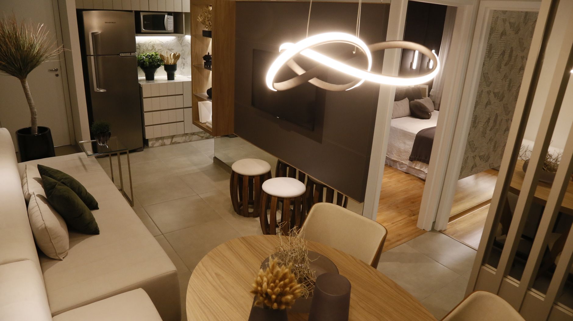 Nowoczesny salon z otwartą kuchnią, neonową lampą, drewnianym stołem i widokiem na sypialnię